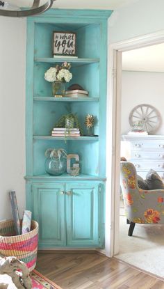 a living room with a blue bookcase and flowers on it's shelves in the corner