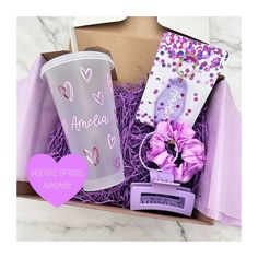 an open box containing a cup, gift card and purple hair bow with the words ameria written on it