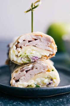 two sandwiches stacked on top of each other on a plate with an apple in the background