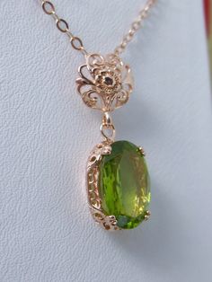 This Edwardian pendant necklace is set with a light natural green peridot. There is delicate floral rose gold filigree surrounding the gem. This lovely reproduction of fine antique filigree jewelry has a full cut oval stone that sparkles with movement while catching the eye. Lovingly crafted by Silver Embrace Jewelry Luxury Peridot Jewelry For Gifts, Elegant Peridot Jewelry For May Birthstone, Elegant Peridot Necklace For Gift, Elegant Jewelry With Intricate Design For May Birthstone, Elegant May Birthstone Jewelry With Intricate Design, Elegant Formal Necklace With Peridot, Elegant Peridot Necklaces For Wedding, Goddess Crystals, Edwardian Pendant