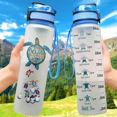 two people holding up water bottles in front of a mountain range with the words ocean on it