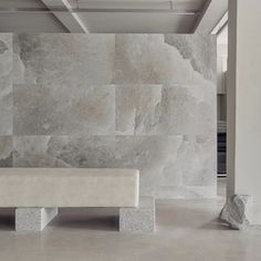 a white bench sitting in front of a wall with stone blocks on it's sides