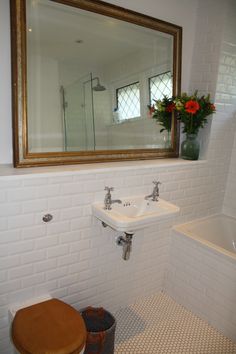 a bathroom with a toilet, sink and mirror in it's corner next to a bathtub