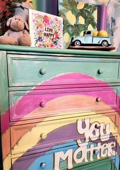 an old dresser painted in bright colors with the words you matter on it and a teddy bear sitting on top