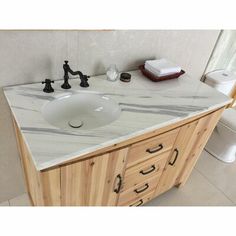 a bathroom with marble counter top and wooden cabinets