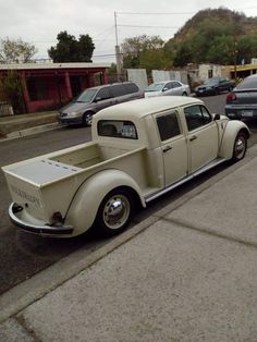 an old truck is parked on the side of the road in front of other cars