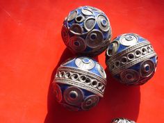 three metal balls sitting on top of a red surface next to each other with circles