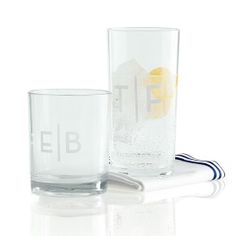 two glasses sitting next to each other on top of a white tablecloth with the letters e and f in it