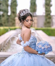 a woman in a blue dress with a tiara on her head holding a bouquet