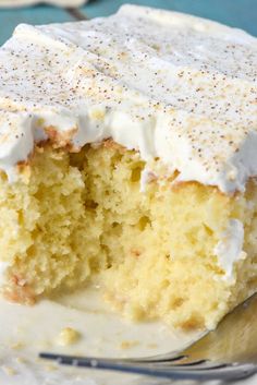 a piece of cake with white frosting on top and a fork in the foreground