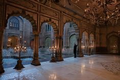 a person standing in an ornate room with chandeliers on either side of it