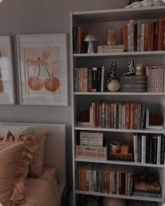 a book shelf filled with lots of books next to a neatly made bed and pillows