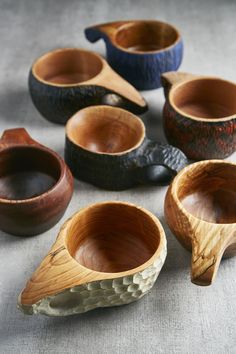 six wooden bowls with different designs and sizes on the table, all lined up next to each other