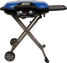 a blue and black grill sitting on top of a white table next to two wheels