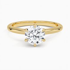 a yellow gold engagement ring with a round cut diamond in the center, on a white background