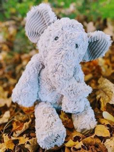 an elephant stuffed animal sitting on top of leaves