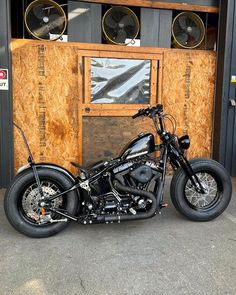 a black motorcycle parked in front of a building with speakers on the wall and wood paneling