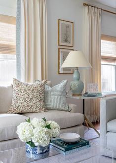 a living room filled with furniture and flowers on top of a coffee table in front of a window