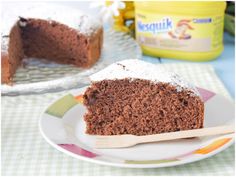 a piece of chocolate cake on a plate with a wooden spoon next to it and a can of yogurt in the background