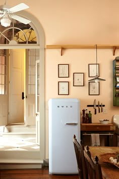 a white refrigerator freezer sitting inside of a kitchen next to a table and chairs