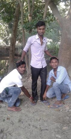 three men are standing in the dirt by some trees