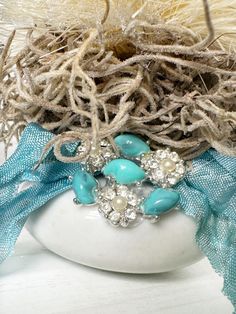 a close up of a bird nest with blue beads and pearls on it's head