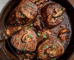 a skillet filled with meat and mushrooms covered in gravy