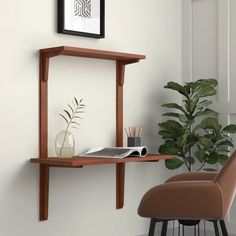 a desk with a chair and potted plant on it in front of a white wall