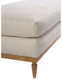 an upholstered footstool with wooden legs and a white linen cover on it