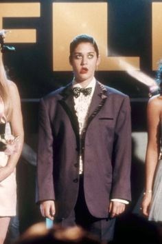 three people standing in front of a sign with the word life on it and one person wearing a tuxedo