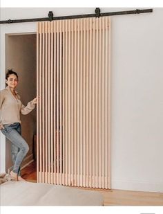 a woman standing in front of a sliding door with wooden slats on the side