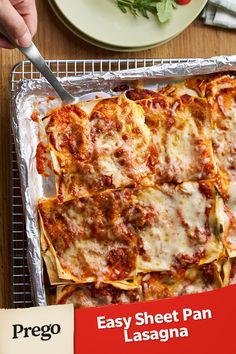 a pan filled with lasagna covered in cheese and sauce next to a plate of salad