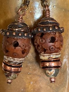 Listen closely and you may hear these earrings beaconing to those who resonate with and earthy, rustic style. The primary focal bead is an intricately carved wooden bead topped with two beautifully made Anna Bronze caps. Below the wood bead is shell "cap", copper spacer bead, and etched agate bead and a tiny copper bead.  The main body of the earring is about 1", with the ear wire the drop length is 1&3/4". The widest point at the dotted bead cap is 1/2".  Feel free to message me if you have any questions and thanks for your interest! Unique Brown Beaded Earrings As Gift, Unique Brown Beaded Earrings For Gift, Artisan Nickel-free Rust-colored Jewelry, Unique Rust-colored Earrings With Ear Wire, Unique Rust Earrings With Ear Wire, Artisan Rust-colored Nickel-free Jewelry, Artisan Rust Color Nickel-free Jewelry, Earthy Copper Jewelry For Festivals, Artisan Copper Beaded Earrings As Gift