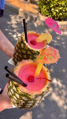 two pineapples with drinks in them and umbrellas sticking out of the top