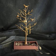 a gold tree with birds sitting on top of it in a pink box next to a black background