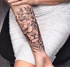 a woman's arm with flowers and a lion tattoo on it