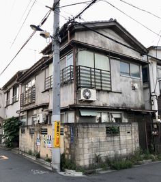 an old run down building on the corner of a street with power lines above it