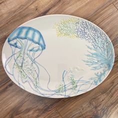 a blue and white jellyfish plate on a wooden floor with seaweed in the background