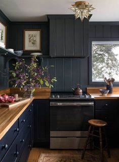 a kitchen with dark blue cabinets and wooden counter tops is pictured in this image, there are two stools next to the stove