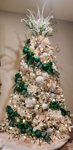 a white christmas tree with green and silver ornaments