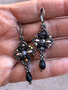 These vintage look, Jet black, Smokey grey and galvanized dk. grey seed bead and drop bead make this lovely set of beaded earrings a must for your jewelry collection. Each pair is hand sewn and woven into a gorgeous design to make a lovely pair of drop earrings. They are lightweight and comfortable to wear. All pieces have stainless steel components for those with sensitive ears.  DIMENSIONS - Length: 1 5/8 inches  - Width: 7/8 inches JEWELRY IS MADE OF.... - Made of assortment of seed beads and a jet black drop. - FireLine Jewelry Thread for durability - Stainless steel components  JEWELRY CARE INSTRUCTIONS  - Keep away from moisture  - When not in use, store in a closed box or zip bag. - Allow perfumes, oils and lotions to dry before wearing jewelry. - Remove before showering and enterin Victorian Style Earrings, Black Drop Earrings, Black Smokey, Wearing Jewelry, Jewelry Care Instructions, Drop Beads, Sensitive Ears, Gorgeous Design, How To Make Beads