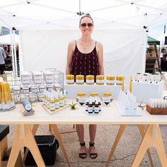 a woman standing in front of a table full of bottles and jars filled with liquid