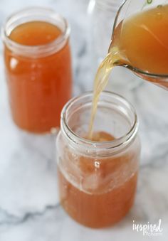 someone pouring honey into jars on a marble table