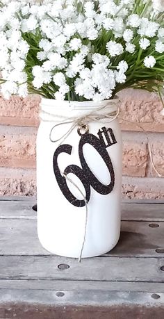 white flowers in a mason jar with the number 60 on it