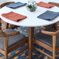 a white table topped with two chairs and a potted plant on top of it