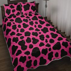 a pink and black cow print comforter on a bed