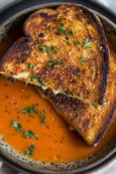 two pieces of toasted bread sit in a bowl of tomato soup