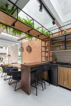 an outdoor kitchen with wooden cabinets and black chairs