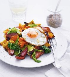 a white plate topped with bacon, lettuce and an egg next to a glass of milk