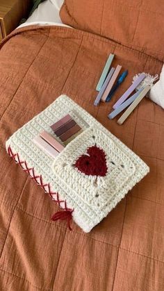 there is a crocheted book on the bed with some books and pencils next to it